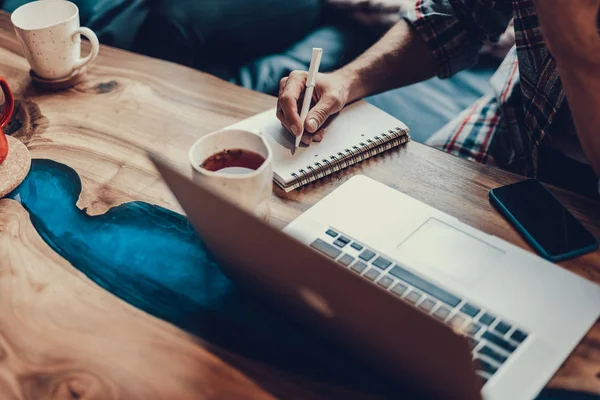 Man writing notes in paper notebook by pen