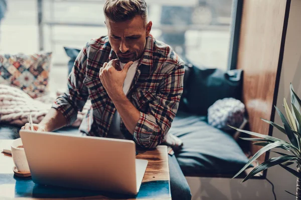 Homme adulte regardant moniteur d'ordinateur portable et assis dans un café — Photo