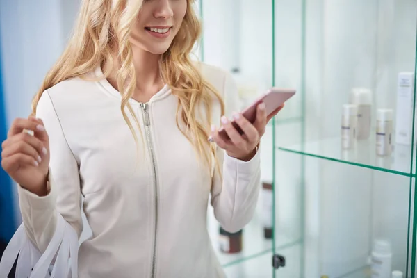 Junge Frau benutzt Handy in Schönheitssalon — Stockfoto