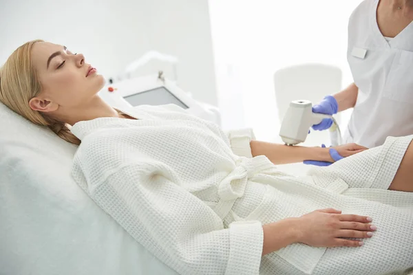 Attractive young lady with closed eyes receiving laser epilation in beauty salon — Stock Photo, Image