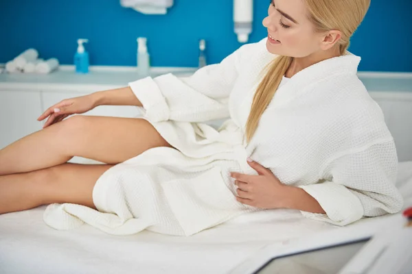 Menina bonita desfrutando de resultados de epilation enquanto descansa no armário cosmetologist — Fotografia de Stock