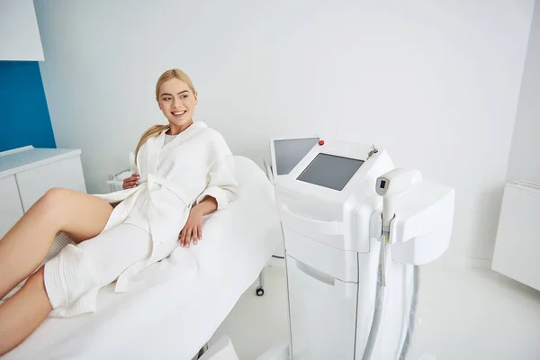 Menina alegre bonita descansando no armário cosmetologist antes do procedimento — Fotografia de Stock