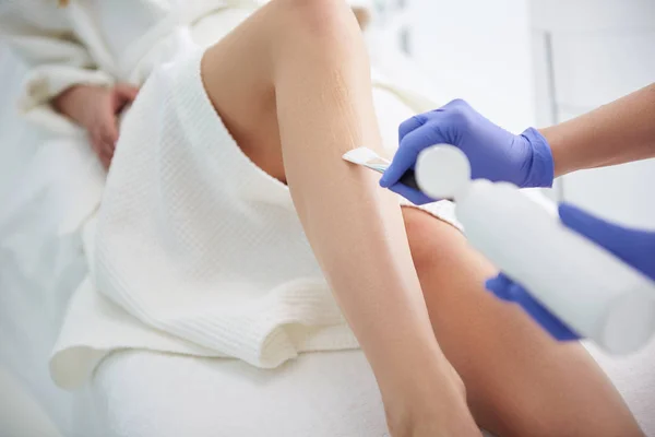 Kosmetolog tillämpa klar gel på kvinna ben före epilering — Stockfoto