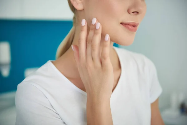 Giovane signora delicatamente toccando il suo viso con pelle liscia perfetta — Foto Stock