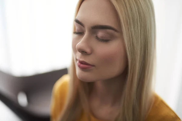 Schöne junge Frau mit glatten blonden Haaren, die friedlich die Augen schließt — Stockfoto