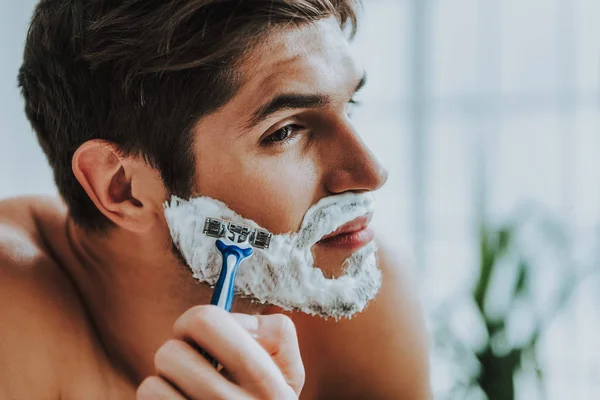 Atraente cara barbear sua barba por navalha — Fotografia de Stock