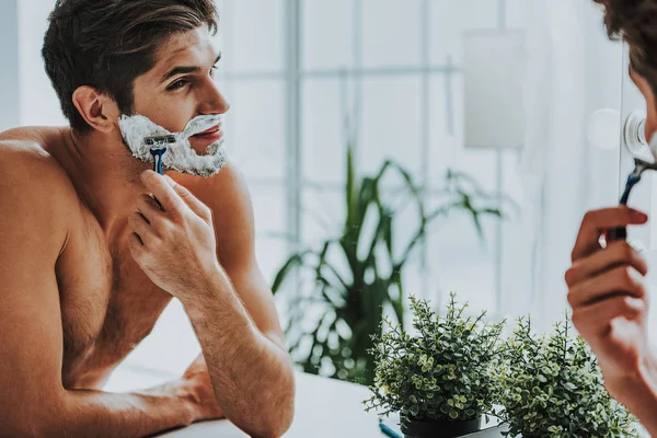 Smiling guy shaving his beard by razor — Stock Photo, Image