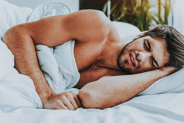 Молодой напряженный мужчина лежал в постели и видеть плохой сон — стоковое фото