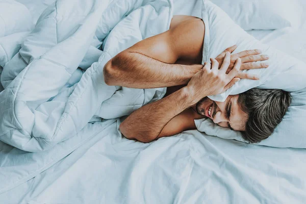 Tipo desesperado presionando almohada en su cabeza —  Fotos de Stock