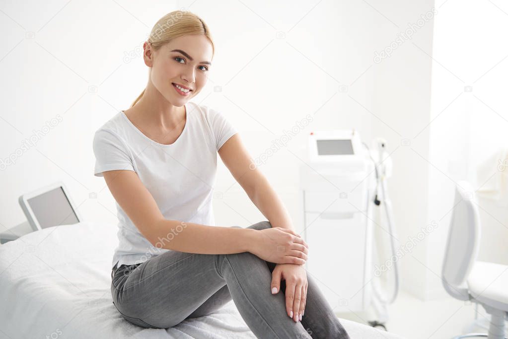 Beautiful young lady sitting on daybed in wellness center