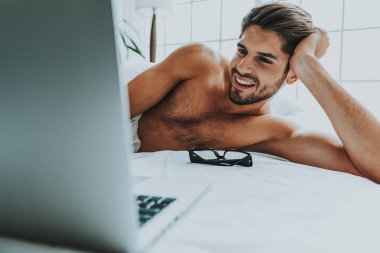 Mutlu adam iletişim kurmak için yatakta dizüstü bilgisayar kullanma