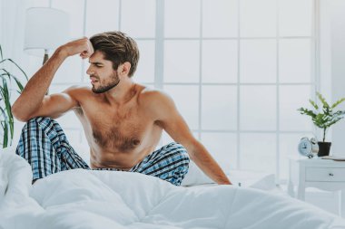 Adam oturup baş ağrısı ile yatakta