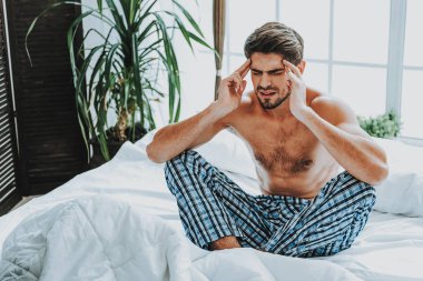 Adam oturup korkunç baş ağrısı ile yatakta