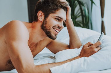 Mutlu adam yatakta tarafından cep telefonu mesajlaşma