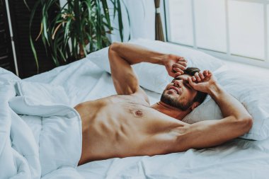 Evde yatakta uzanan gülümseyen genç adam