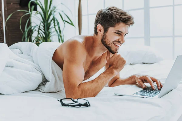 Chico alegre usando el ordenador portátil en la cama para comunicarse — Foto de Stock