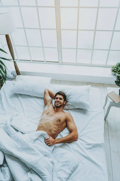 Счастливый парень просыпается в постели дома — стоковое фото