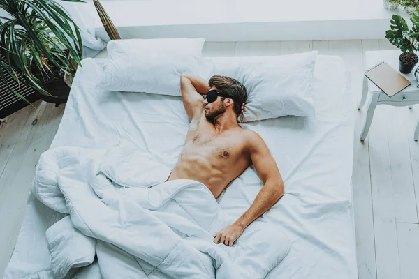 Joven hombre atractivo dormir con los ojos vendados en la cama —  Fotos de Stock