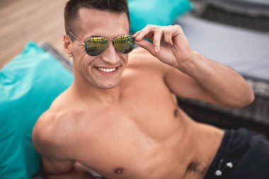 Güneş gözlüklerini dokunmaktan ve gülümseyen yakışıklı dostça adam