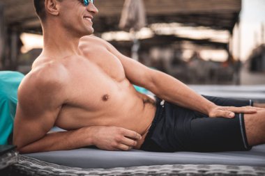 Bacağına bir el koyarak ve gülümseyen çekici gömleksiz adam