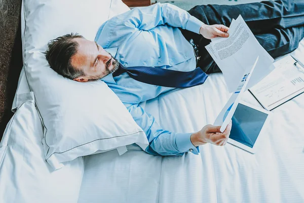 Vista superior del hombre de negocios mirando documentos mientras está en la cama — Foto de Stock