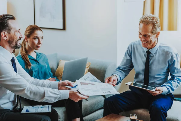 Man and woman sitting on the sofa and happy businessman taking graphic — Stock Photo, Image