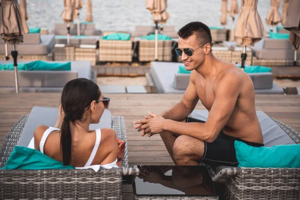 Homem positivo sentado na espreguiçadeira e conversando com uma jovem — Fotografia de Stock