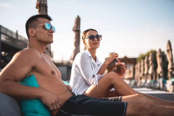 Hombre joven relajándose en la playa y su novia bebiendo cóctel — Foto de Stock