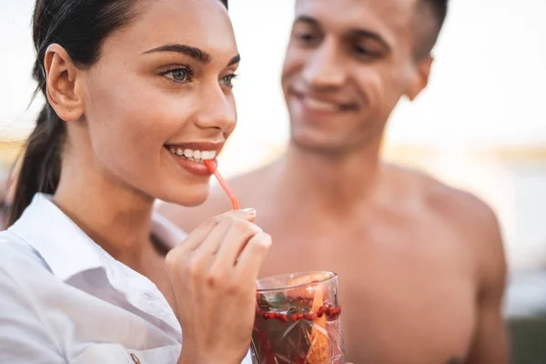 Primer plano de la mujer sonriente bebiendo cóctel a través de la paja sorbiendo — Foto de Stock