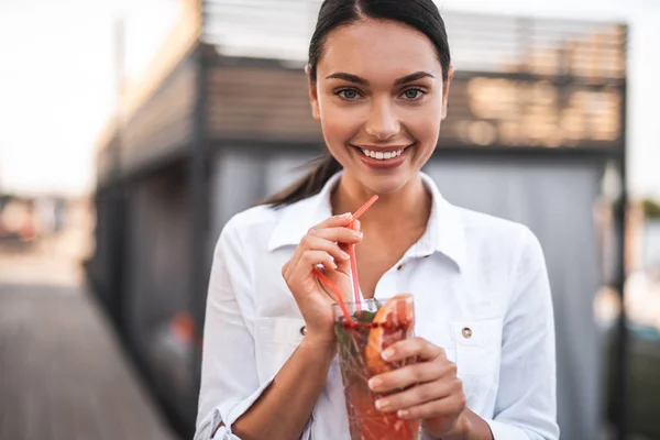 Cheerful pretty lady smiling while standing with cocktail — Stock Photo, Image