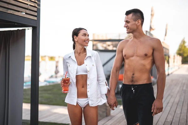 Alegre sem camisa homem andando com jovem senhora em maiô — Fotografia de Stock