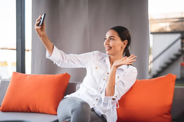 Cute young lady waiving her hand while having video call — Stock Photo, Image