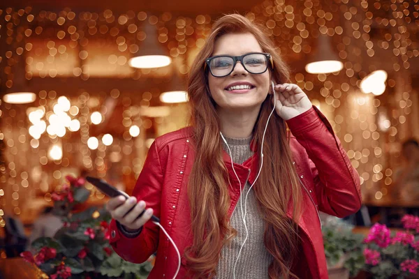 Atractiva chica pelirroja escuchando música en el teléfono inteligente — Foto de Stock