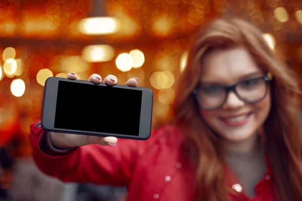 Encantadora jovencita sosteniendo teléfono inteligente con pantalla negra — Foto de Stock