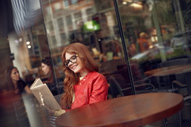 Kitap okuma ve gülümseyen güzel kızıl saçlı kız