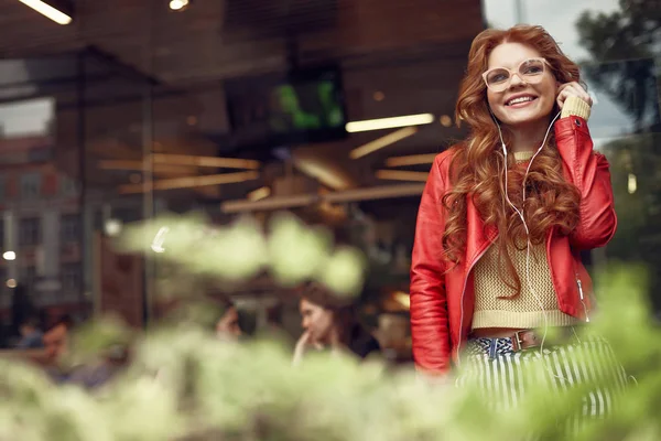 Hermosa chica pelirroja pasar tiempo al aire libre y disfrutar de la música — Foto de Stock