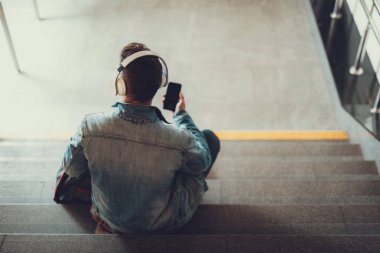 Tanınmayan adam merdivenlerde oturan ve mp3 ses dinleme