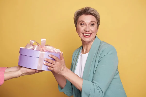 Meio comprimento de mãe bonita feliz recebendo um presente no fundo amarelo — Fotografia de Stock