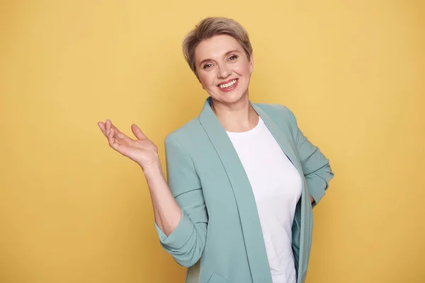Gelukkig charmante moeder poseren in studio tegen gele muur — Stockfoto
