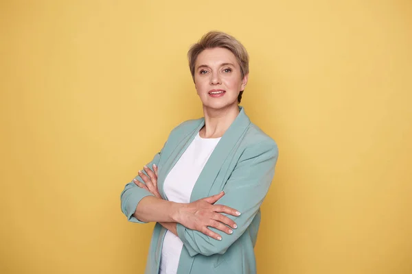 Calma mãe bonita posando no estúdio contra a parede amarela — Fotografia de Stock