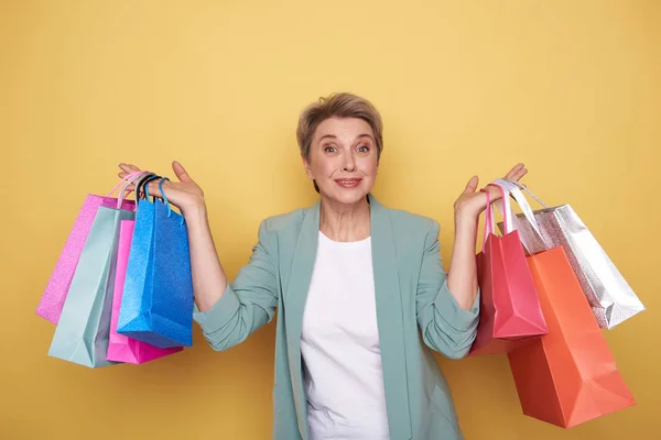 Zaskoczony, szczęśliwą kobietą, patrząc na aparat z torby na zakupy w ramionach — Zdjęcie stockowe