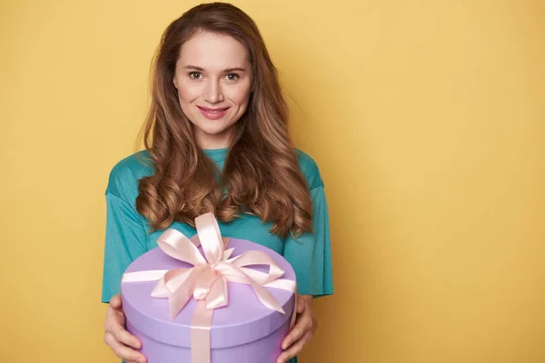 Половина довжини усміхненої дівчини тримає подарунок в руках в приміщенні — стокове фото