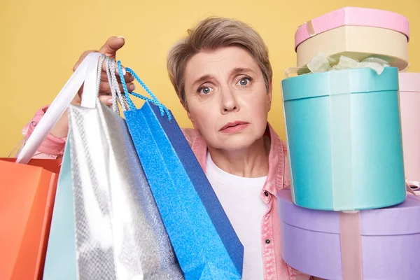 Portrait of unhappy mother situating between presents and shopping bags — Stock Photo, Image