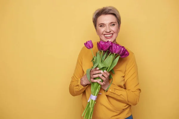 Портрет чарівної усміхненої жінки з милим букетом тюльпанів на руках — стокове фото
