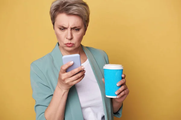 Primo piano di donna infelice che guarda lo schermo del cellulare in studio — Foto Stock