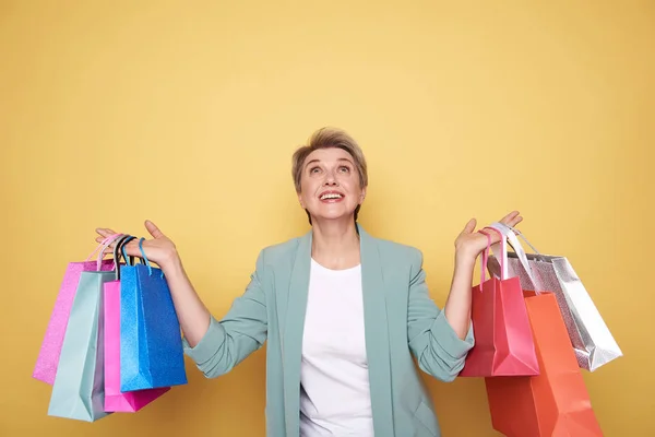 Mujer feliz mirando hacia arriba con bolsas de compras en sus brazos —  Fotos de Stock