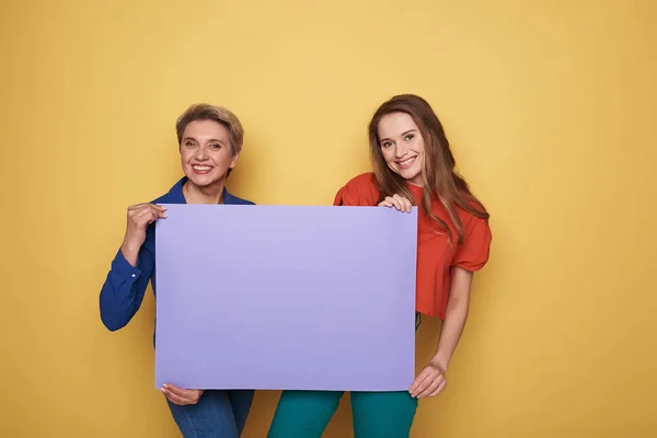 Обрізаний фото щасливі кавказьких жінок, тримаючись за фіолетові порожній плакат студії — стокове фото