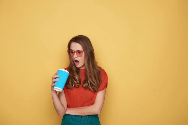 Taille van zenuwachtig meisje houden cupholder in arm tegen oranje achtergrond — Stockfoto