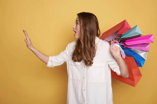 Vista lateral de la hermosa mujer joven sosteniendo bolsas de compras y la captura de taxi — Foto de Stock