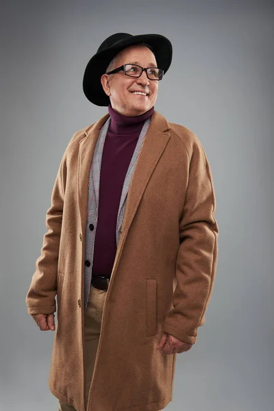 Ενήλικα άνδρα χαμογελώντας ενώ φορώντας μακρύ παλτό και καπέλο — Φωτογραφία Αρχείου